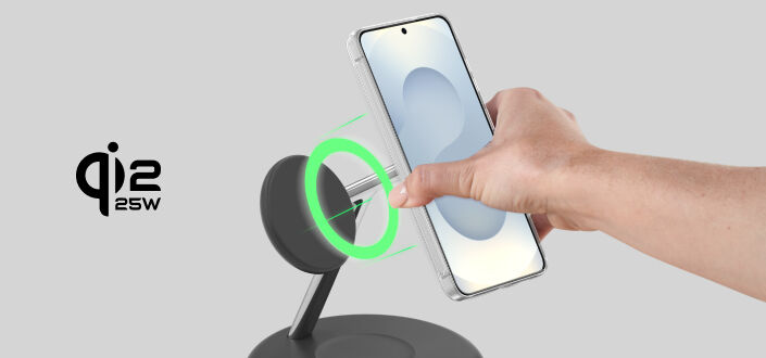 Hand placing a smartphone onto a magnetic wireless charging stand, with a green ring indicating alignment and &lsquo;Qi2 25W&rsquo; charging shown beside it.