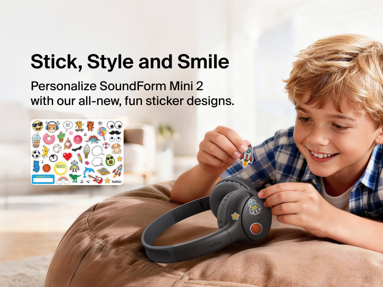 Child applying decorative stickers to the SoundForm Mini 2 Wireless On-Ear Headphones for Kids, with a full sticker sheet visible featuring playful emoji-style designs and a name label
