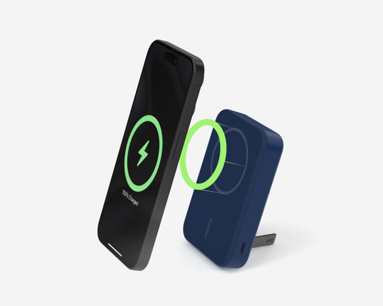 Ein Smartphone, das kabellos auf einem MagSafe-kompatiblen Belkin Ladegerät aufgeladen wird und mit einem einklappbaren Ständer aufgestellt ist. Ein grün leuchtender Ring veranschaulicht die magnetische Verbindung zwischen Handy und Ladegerät.
