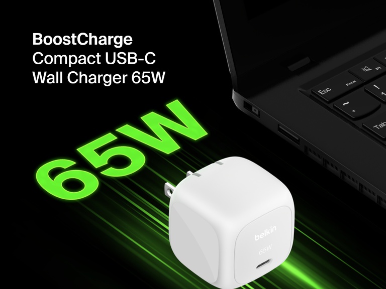 Angled image of the Belkin BoostCharge Compact USB-C Wall Charger 65W beside a laptop, highlighting its fast-charging capability with bold green "65W" text for emphasis.