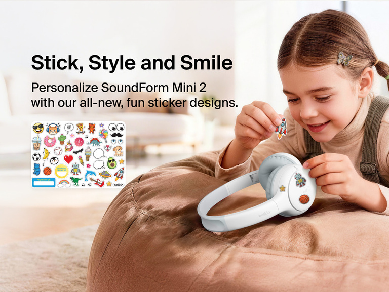 Child applying decorative stickers to the SoundForm Mini 2 Wireless On-Ear Headphones for Kids, with a full sticker sheet visible featuring playful emoji-style designs and a name label