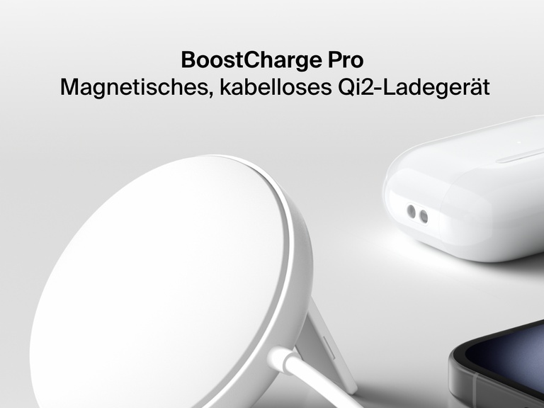 Ein weißes, magnetisches, kabelloses  Belkin BoostCharge-Ladegerät mit Qi2 und 15 Watt wird hochgestellt auf einer weißen Oberfläche neben einem iPhone und einem Paar weißer AirPods in ihrem Ladecase gezeigt. 