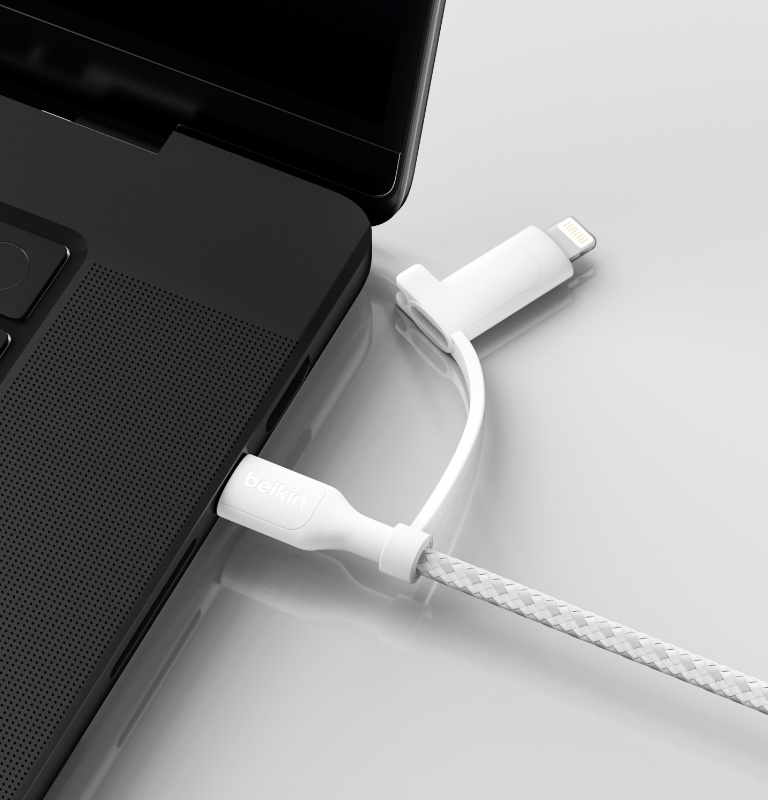 Un câble 2-en-1 BoostCharge Pro avec connecteurs USB-C et Lightning branché sur le port USB-C d'un ordinateur portable, posé sur une surface plane blanche.