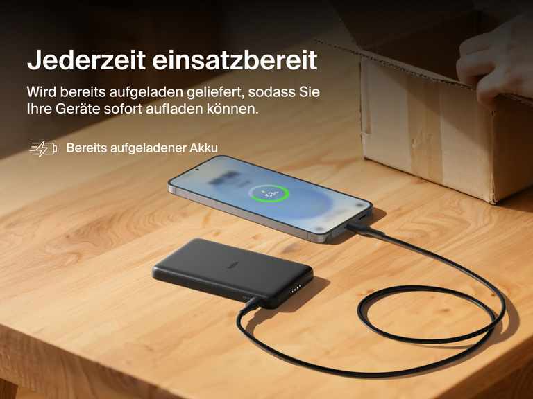 Belkin BoostCharge Slim Magnetic Power Bank 5K shown charging a smartphone on a table, highlighting its precharged battery ready for instant use out of the box.