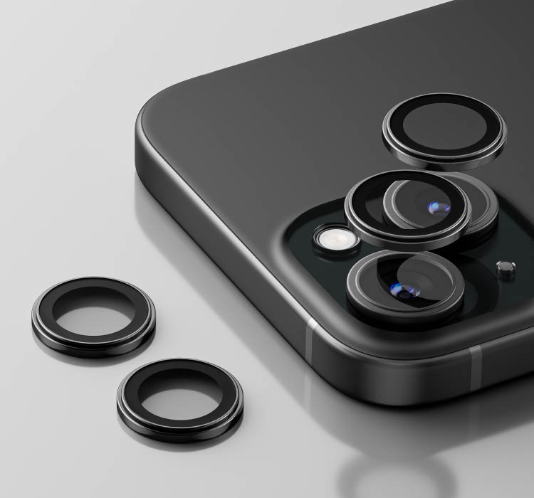 Close-up of a black iPhone with a ScreenForce TemperedGlass Camera Lens Protector partially attached, with two loose lens protectors placed nearby on a reflective surface.