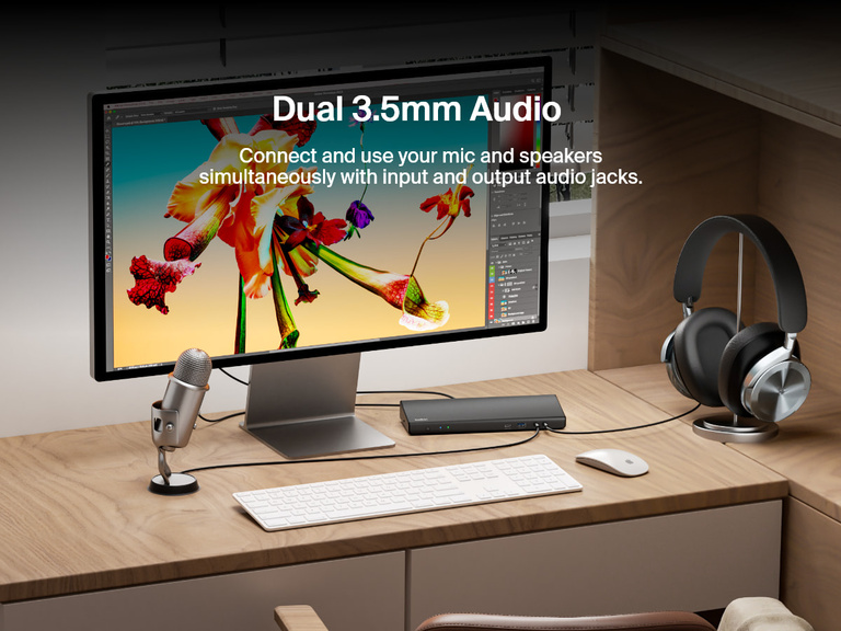 The Belkin Connect Universal USB-C Triple Display Dock is shown on a desk setup with a connected microphone and headphones, highlighting its dual 3.5mm audio jacks for simultaneous input and output use.