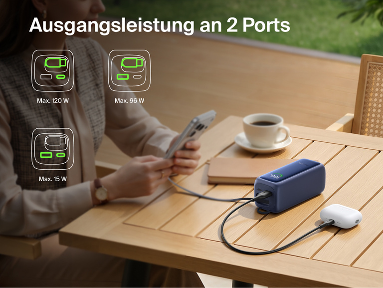 UltraCharge Powerbank 22K mit einziehbarem Kabel, die an einem Tisch ein Smartphone und ein Ladecase f&uuml;r In-Ear-Kopfh&ouml;rer &uuml;ber zwei Anschl&uuml;sse gleichzeitig l&auml;dt, mit Symbolen f&uuml;r die verf&uuml;gbaren Leistungskombinationen.