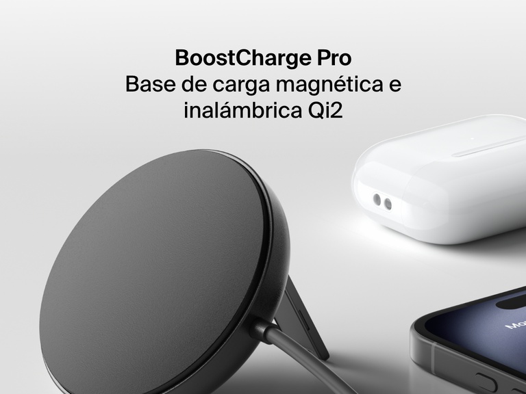 Se muestra una base magnética de carga inalámbrica con Qi2 de 15 W BoostCharge de Belkin de color negro, en posición erguida sobre una superficie blanca y junto a un iPhone y un juego de AirPods en su estuche de carga.
