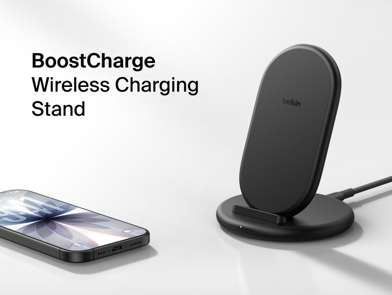 Belkin BoostCharge Wireless Charging Stand 15W shown with smartphone nearby, featuring a sleek upright design for fast wireless charging.