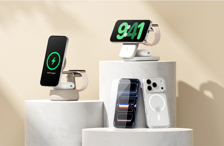 Minimalist product display with Belkin accessories on white marble pedestals, including a beige magnetic charging stand, a white wireless charging dock, and a clear screen protector.