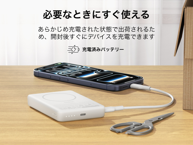 Belkin BoostCharge薄型マグネット式モバイルバッテリー10Kは、箱から出してすぐに使える状態で、USB-Cケーブルを介してスマートフォンを充電し、ポータブルバッテリーが机の上に置かれています。