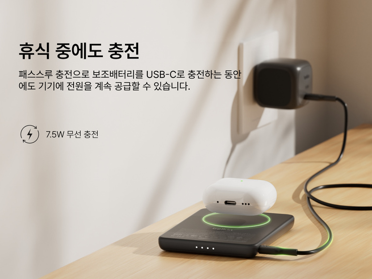 Belkin BoostCharge Slim Magnetic Power Bank 5K shown wirelessly charging earbuds while recharging via USB-C, demonstrating 7.5W pass-through charging functionality.
