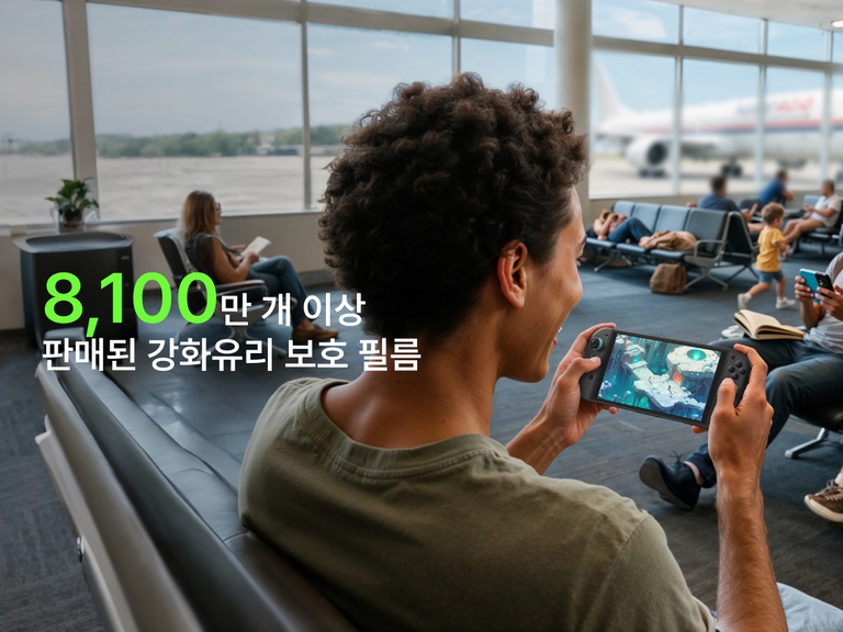 공항 게이트에서 Nintendo Switch 2로 게임을 플레이하며 미소를 짓는 청년. 배경에서는 다른 여행객들이 앉아서 책을 읽거나 휴대전화를 사용하고 있고, 창문 너머로 비행기가 보입니다. 전경의 큰 녹색 글씨에는 &ldquo;8,100만 개 돌파&rdquo;, 그 아래의 흰색 글씨에는 &ldquo;화면 보호용 강화 유리 판매량&rdquo;이라고 적혀 있어 해당 제품의 인기를 강조하고 있습니다.