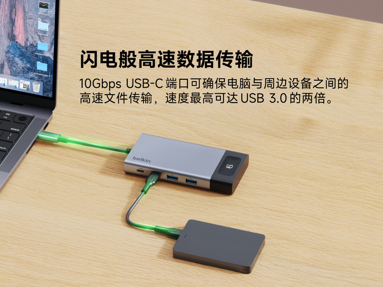 桌面上的贝尔金 USB-C 连接到笔记本电脑和外置硬盘，突出展示设备之间高达 10Gbps 的高速数据传输。