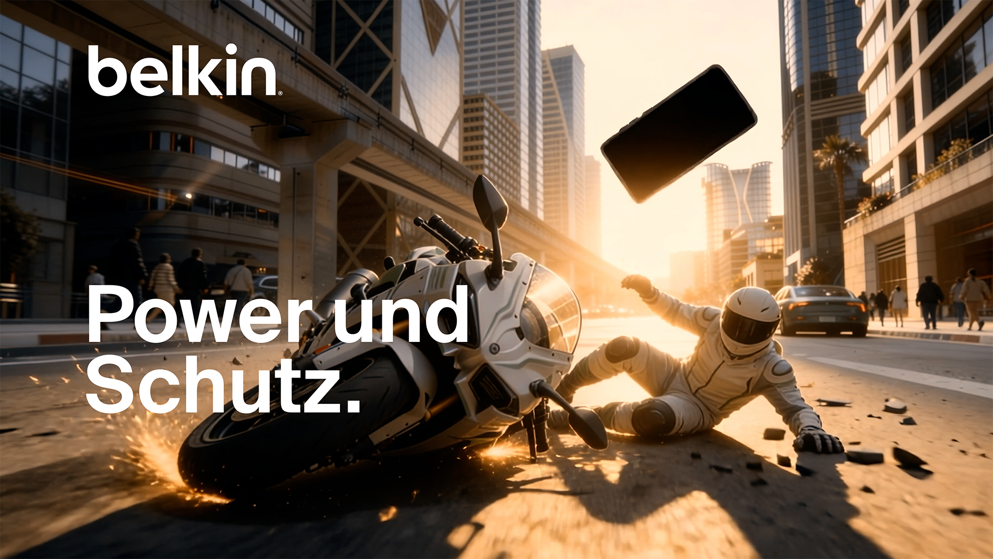 Belkin &bdquo;Power und Schutz&rdquo; Video-Miniaturansicht mit einer Motorradfahrerin, die auf einer Gro&szlig;stadtstra&szlig;e ausrutscht. Ein Smartphone fliegt durch die Luft, wodurch die Robustheit und der Ger&auml;teschutz betont werden.