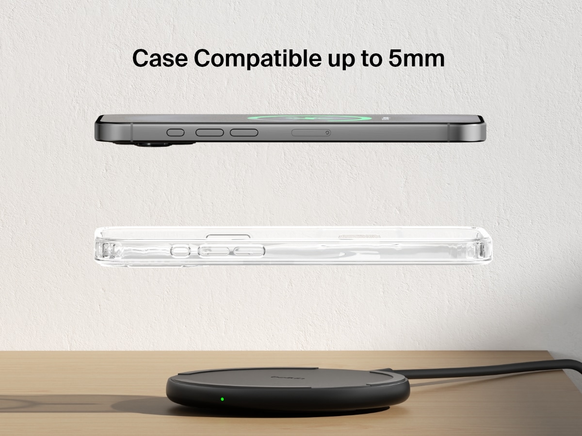 A black Belkin BoostCharge Wireless Charging Pad 15W is shown on a wooden surface with an iPhone and a transparent case floating above it, highlighting its compatibility with cases up to 5mm thick.