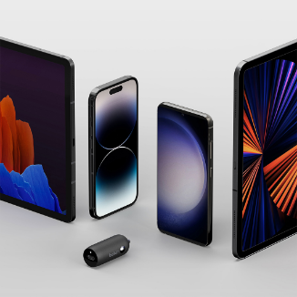 A collection of modern electronic devices including two tablets, two smartphones, and a small cylindrical wired car charger displayed upright on a neutral background. The screens of the devices show vibrant and colorful graphics.