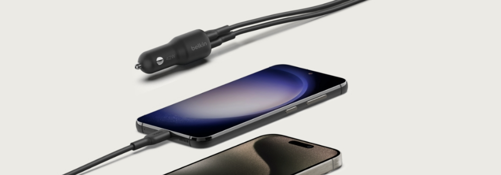 Two smartphones connected via USB-C cables to a Belkin dual-port car charger, designed for use with a 12V car power outlet, displayed against a neutral background.
