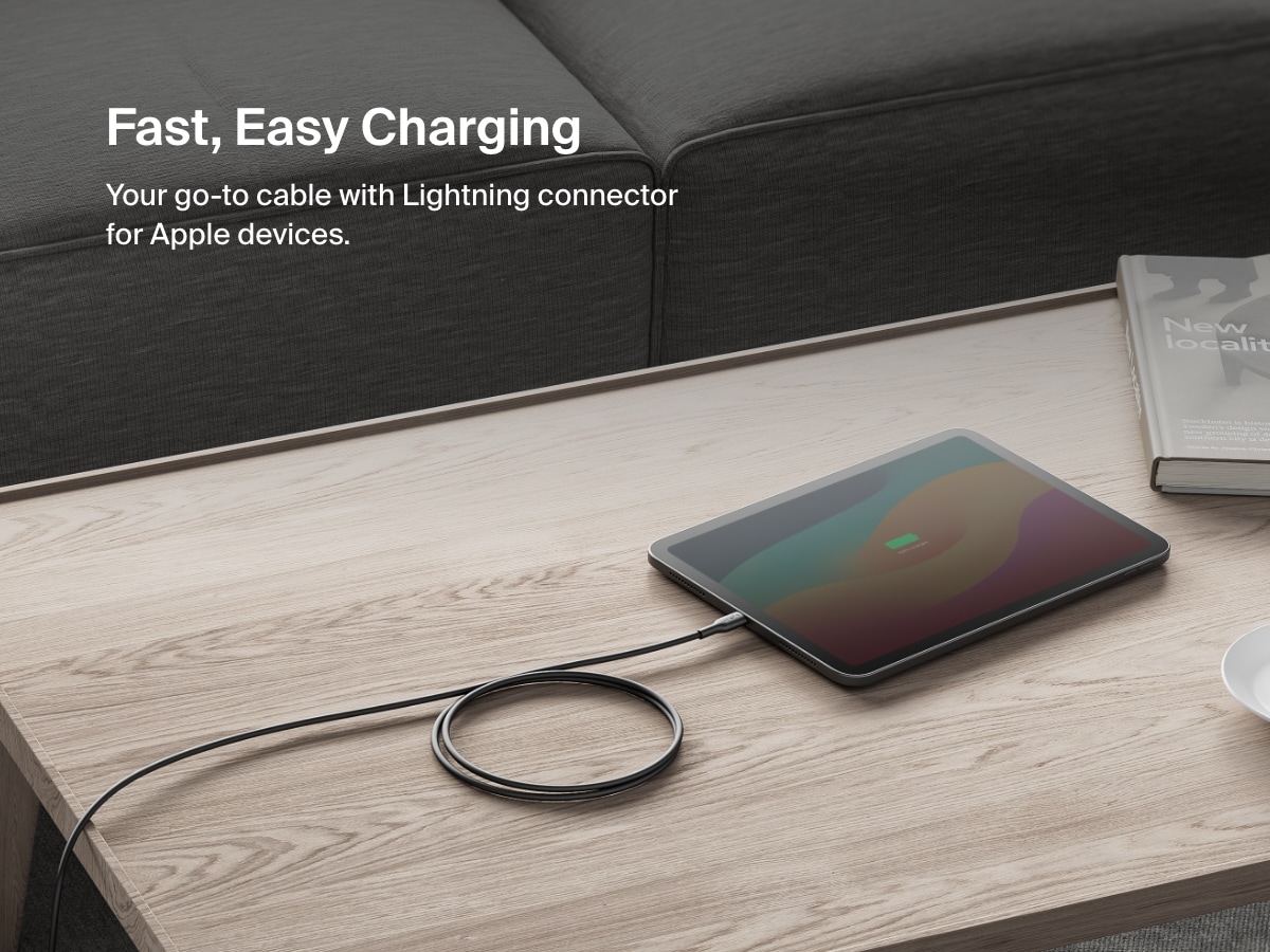 Belkin BoostCharge USB-C Cable with Lightning Connector shown charging an iPad on a coffee table, highlighting fast and easy charging for Apple devices.