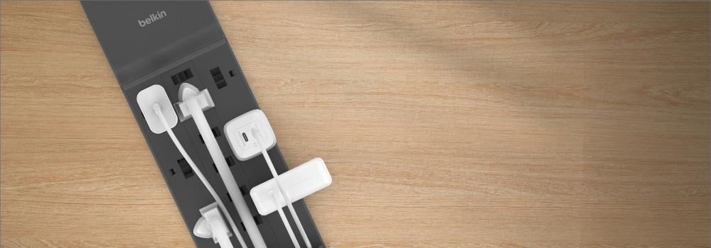 **Alt text:** Top-down view of a Belkin 12-Outlet Home/Office Surge Protector with multiple devices and power adapters plugged into widely spaced outlets.
