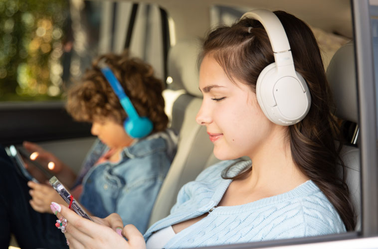 Kids wearing Belkin wireless headphones and watching tablet during family travel
