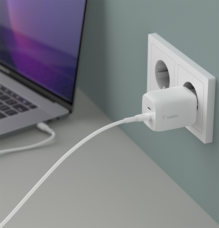 Imagen de un cargador de pared doble USB-C® GaN con PPS de 65 W siendo utilizado, enchufado en una pared y con un cable USB-C conectado en su puerto inferior.
