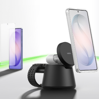 A smartphone mounted on a black magnetic charging stand, with a screen protector and another phone visible in the background, set against a clean surface with a subtle green accent line.