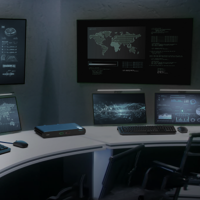 A modern cybersecurity operations center with multiple computer screens displaying data, analytics, and world maps. The room has a dark ambiance, with a curved workstation equipped with laptops, keyboards, and a secure network device. The monitors show real-time cybersecurity threat intelligence and system monitoring information. The setup suggests a high-tech environment for cybersecurity professionals.