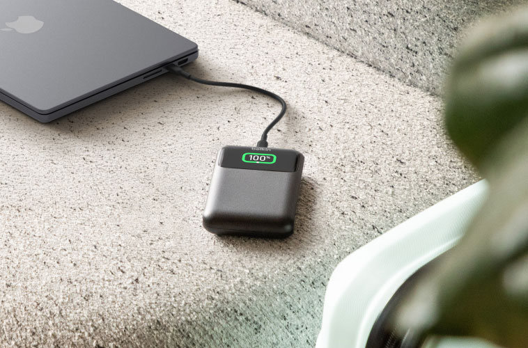 High-capacity USB-C laptop power bank charging MacBook on hotel floor during travel