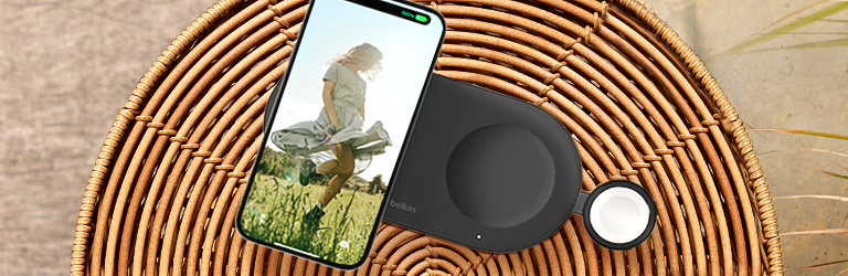 A Belkin 3-in-1 wireless charging pad powers an iPhone and Apple Watch on a wicker table, highlighting MagSafe convenience and summer-ready tech.
