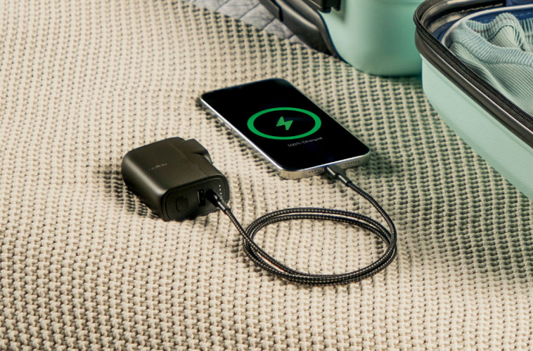 Compact USB-C travel power bank with wall plug packed in suitcase next to folded clothes